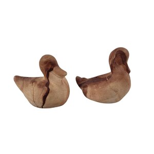 May include: Two brown ceramic duck figurines with a marbled pattern. The ducks are facing different directions.