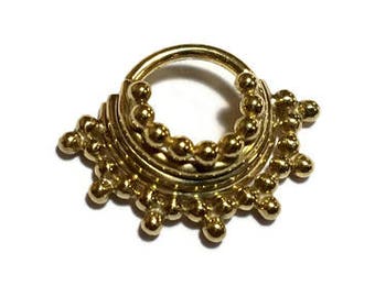 May include: Gold septum ring with a beaded design. The ring has two rows of beads, with a larger bead at the top and bottom of each row.