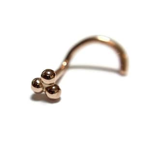 May include: A rose gold nose ring with a cluster of three small balls at the end.