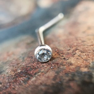 May include: A silver nose ring with a clear crystal gemstone.