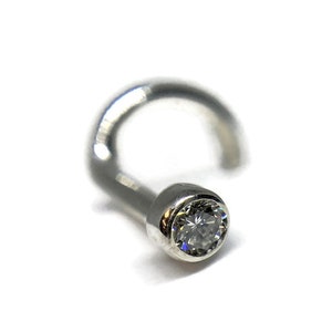 Puede incluir: Un aro de nariz de plata con una piedra redonda transparente.