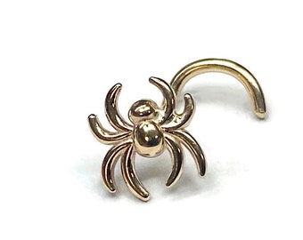 May include: Gold nose ring with a spider design. The spider is detailed with eight legs and a round body.
