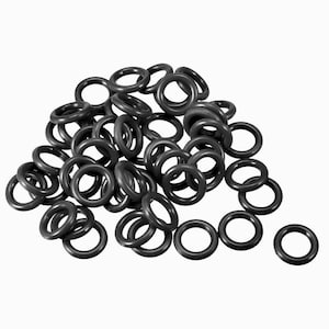 May include: A pile of numerous black rubber O-rings. The O-rings are circular with a consistent thickness and are made of a matte material. The rings are scattered across a white background.