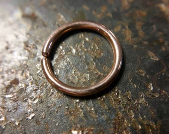 May include: A close-up of a rose gold seamless ring, a type of jewellery often used for body piercings.