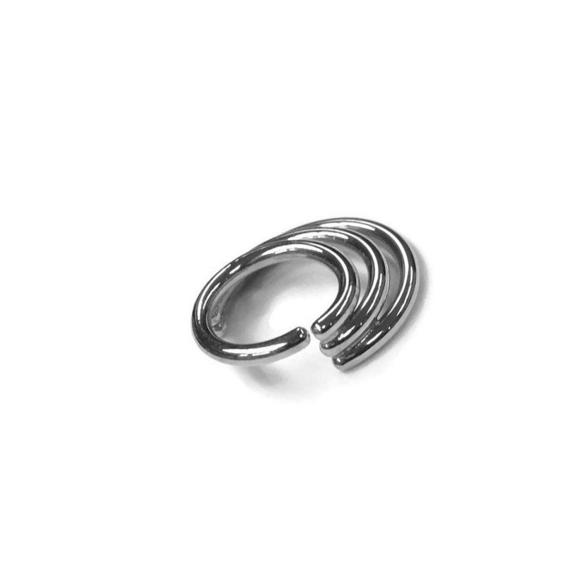 May include: Three silver hoop earrings stacked on top of each other.