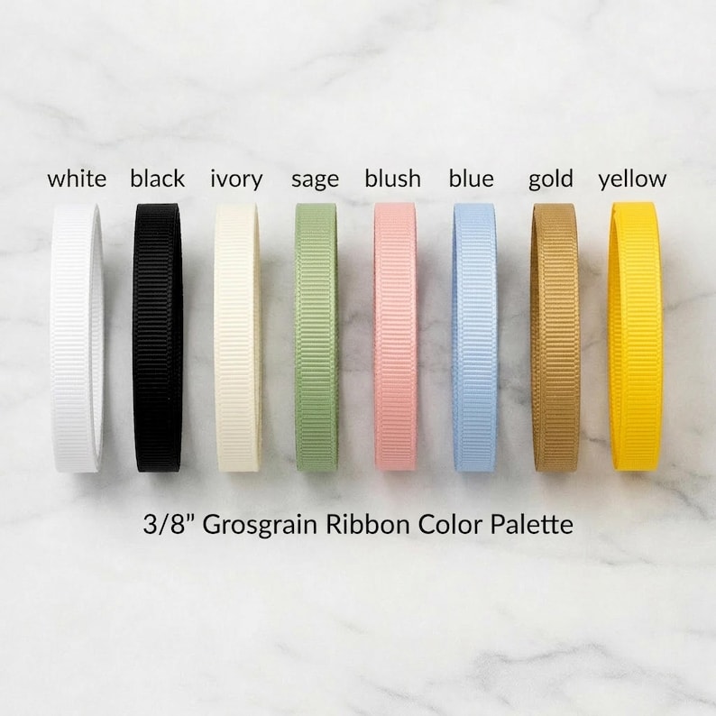 A collection of eight different colored grosgrain ribbons arranged in a row, with each ribbon having a corresponding color label next to it.