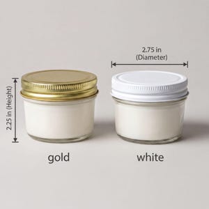 two jars of candle wax, one labeled as gold and the other as white, with a measurement scale indicating their sizes.