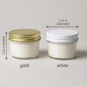two small glass jars with lids, one labeled "gold" and the other "white", placed side by side. The jars appear to be made of glass and have a similar appearance.