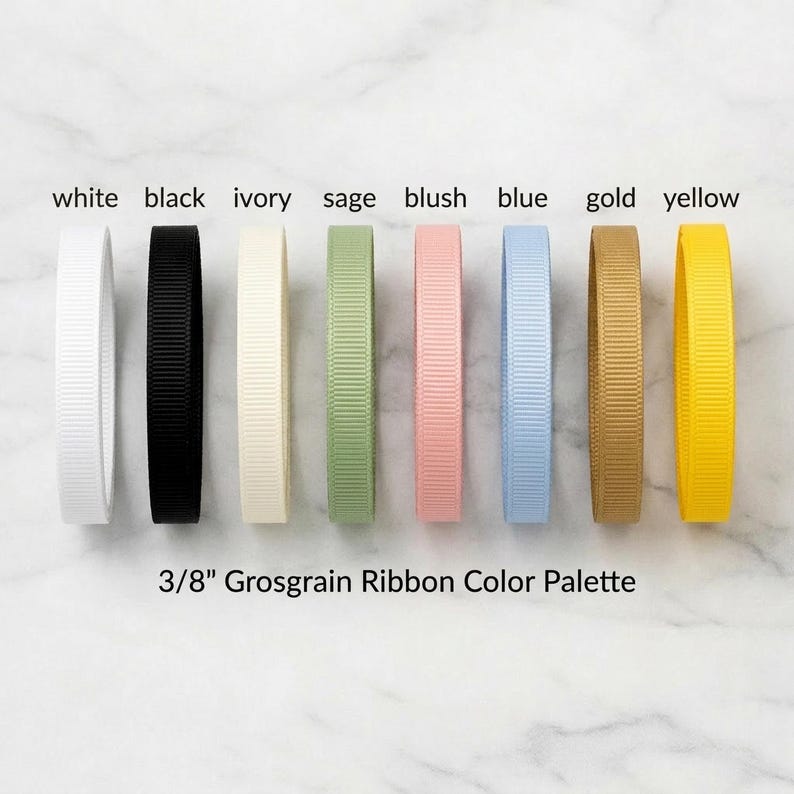 A collection of eight different colored grosgrain ribbons arranged in a row, with each ribbon having a corresponding color label next to it.