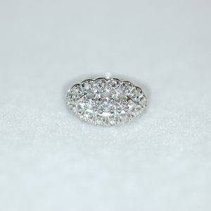 May include: A silver ring with a large oval-shaped cluster of small diamonds.