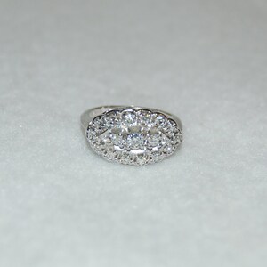 May include: A silver ring with a large oval-shaped cluster of clear cubic zirconia stones.
