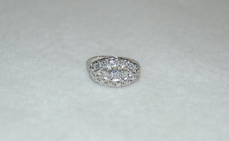 May include: A silver ring with a large oval-shaped cluster of clear cubic zirconia stones.