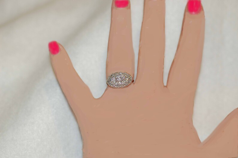 May include: A silver ring with a large oval-shaped center stone surrounded by smaller diamonds.