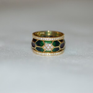 A wide gold band ring featuring a central row of green and dark enamel segments with diamonds, bordered by top and bottom rows of pavé-set diamonds.