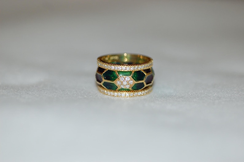 A wide gold band ring featuring a central row of green and dark enamel segments with diamonds, bordered by top and bottom rows of pavé-set diamonds.