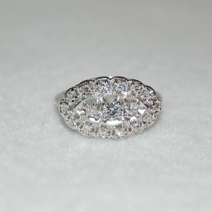 May include: A silver ring with a large oval-shaped center stone surrounded by smaller stones.