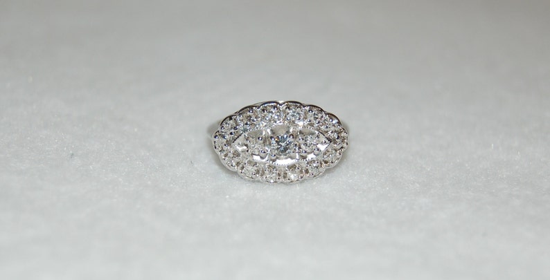 May include: A silver ring with a large oval-shaped center stone surrounded by smaller stones.