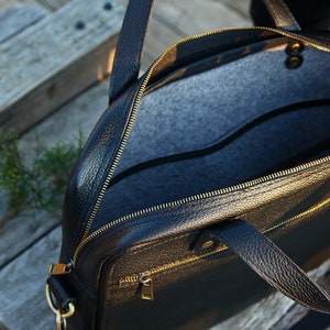 May include: Black leather briefcase with gold zippers and hardware. The bag is open and the interior is lined with gray felt.