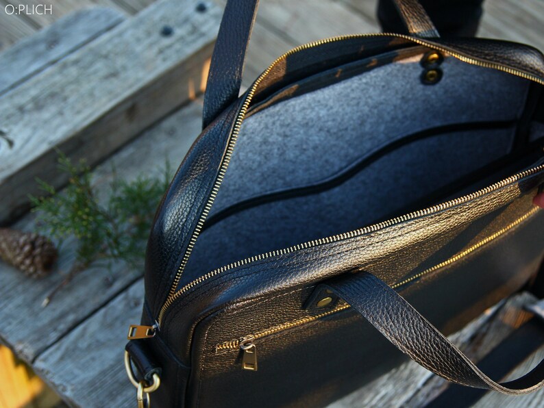 May include: Black leather briefcase with gold zippers and hardware. The bag is open and the interior is lined with gray felt.