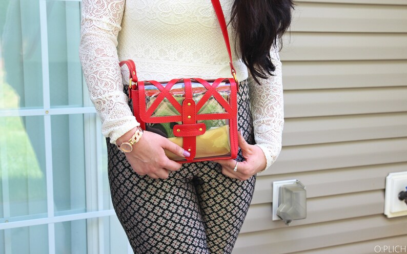 May include: A red and clear crossbody bag with a geometric design. The bag has a gold chain strap and gold accents.