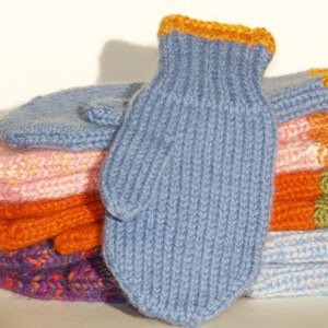 Könnte beinhalten: Ein Stapel gestrickter Fäustlinge in verschiedenen Farben, darunter Blau, Rosa, Orange und Lila. Der oberste Fäustling ist blau mit gelbem Besatz.