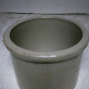 May include: A plain, off-white ceramic crock pot with a wide, round opening.