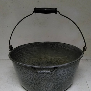 May include: A gray enamelware bucket with a black handle and a wire carrying handle. The bucket has a speckled pattern.