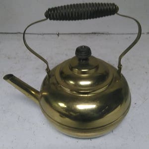 May include: A brass teapot with a black handle and a wooden knob on the lid.