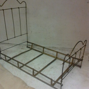 May include: A metal bed frame with a headboard and footboard. The frame is made of thin metal rods and has a simple design.