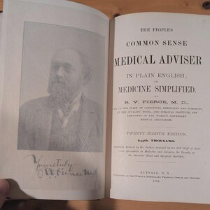 May include: An open antique book titled The People's Common Sense Medical Adviser in Plain English by R. V. Pierce, M.D., 1892. The left page features a black and white portrait of a bearded man with a signature below, and the right page contains text.