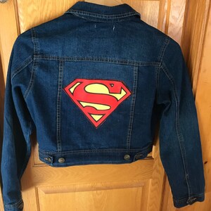 May include: A blue denim jacket with a red and yellow Superman logo on the back.