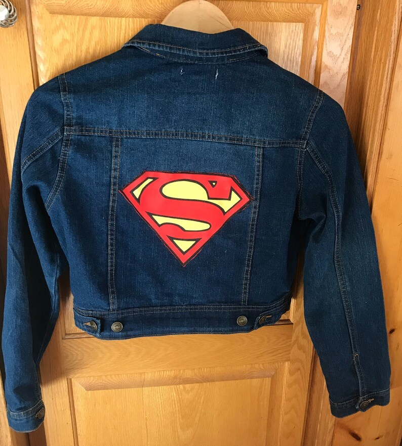 May include: A blue denim jacket with a red and yellow Superman logo on the back.