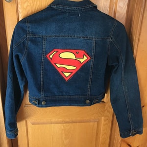 May include: A blue denim jacket with a red and yellow Superman logo painted on the back.