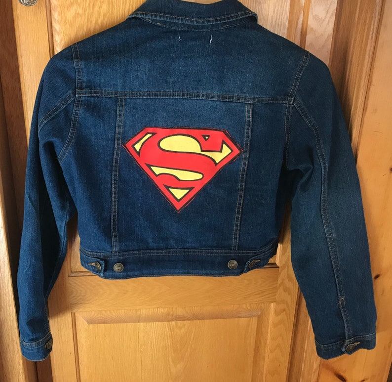 May include: A blue denim jacket with a red and yellow Superman logo painted on the back.