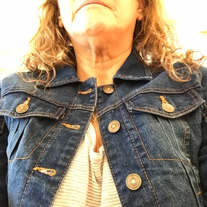 May include: A dark blue denim jacket with a zipper closure and multiple pockets. The jacket has a button-up front and a classic style.