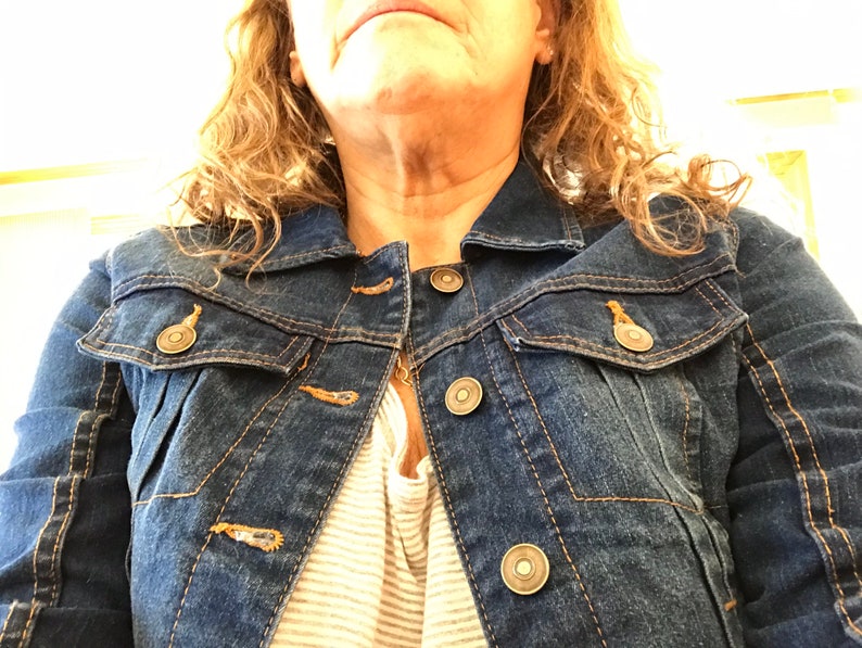 May include: A dark blue denim jacket with a zipper closure and multiple pockets. The jacket has a button-up front and a classic style.