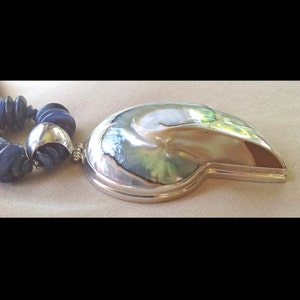 May include: A silver necklace with a large iridescent abalone shell pendant and blue glass beads.
