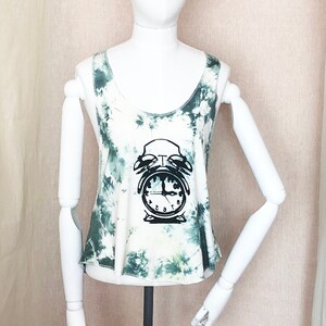 May include: A white tank top with a green tie-dye pattern and a black alarm clock graphic. The clock has Roman numerals and the text "mixxjim" is in a speech bubble in the top right corner.