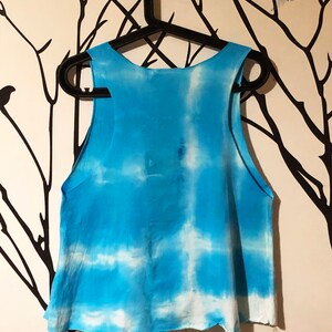 May include: A blue and white tie-dye tank top with a loose fit. The tank top is hanging on a black hanger.