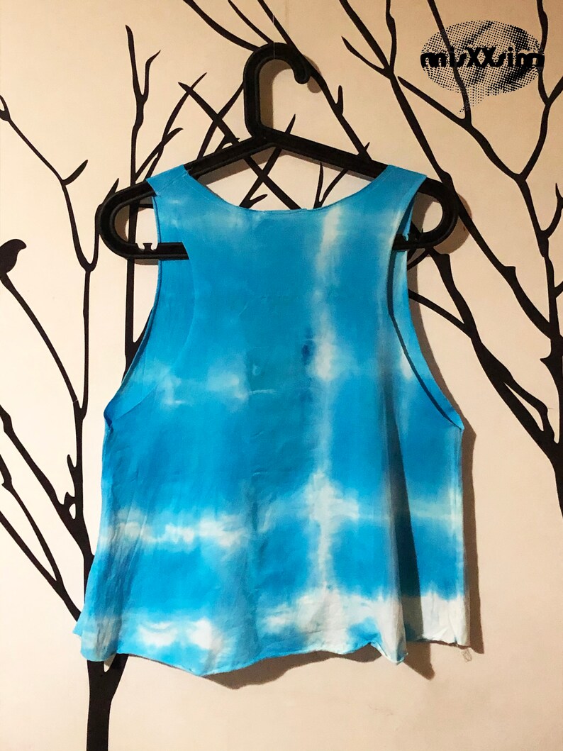May include: A blue and white tie-dye tank top with a loose fit. The tank top is hanging on a black hanger.