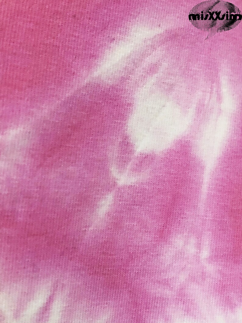 May include: A close-up of a pink and white tie-dye fabric. The fabric has a soft, textured feel and a subtle sheen.