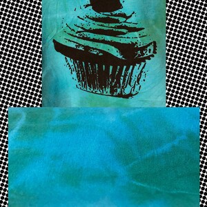 May include: A teal blue tie-dye fabric with a black and white silhouette of a cupcake with a cherry on top.