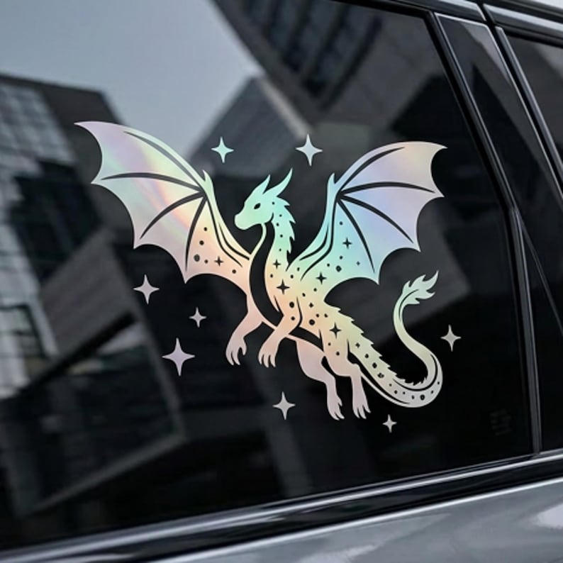 May include: A holographic dragon sticker with outstretched wings and star accents. The dragon is depicted in a detailed, stylized design, with a gradient of colors. The sticker is applied to a car window.