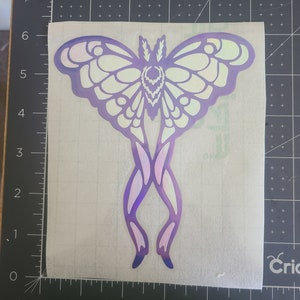 May include: A white and purple iridescent vinyl sticker of a moth with intricate wing details.