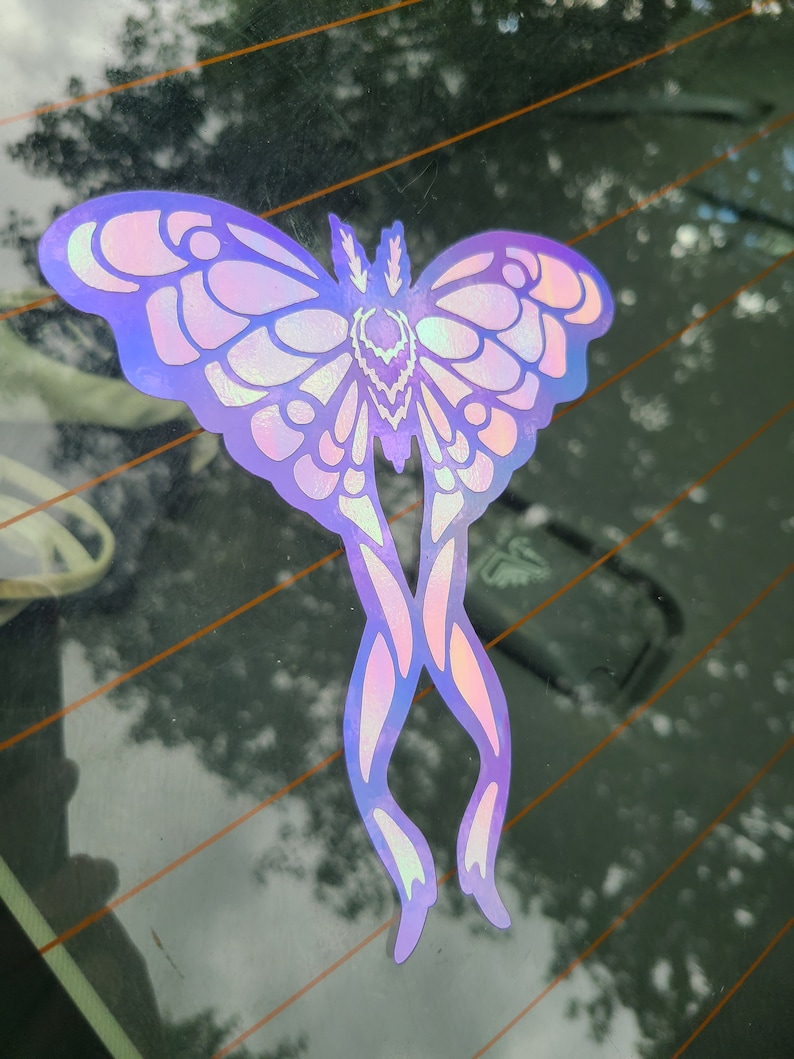 May include: A holographic iridescent butterfly sticker with purple and pink hues. The butterfly has a detailed design with intricate wings and a body.
