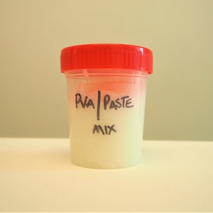 Peut inclure: Un r&eacute;cipient en plastique transparent avec un couvercle rouge rempli d'une p&acirc;te blanche. Le r&eacute;cipient est &eacute;tiquet&eacute; "PVA Paste Mix".