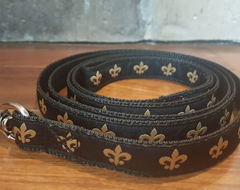 Könnte beinhalten: Schwarze Hundeleine mit goldenem Fleur-de-Lis-Muster und einem silbernen Metallverschluss. Die Leine besteht aus strapazierfähigem Material.