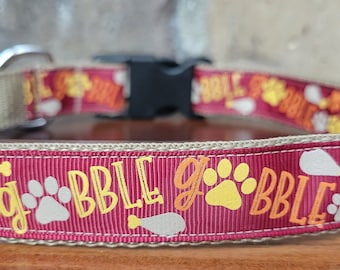 Puede incluir: Un collar de perro rojo con ribete marrón presenta un patrón repetido de huellas de patas, patas de pavo y la palabra "gobble" en letras naranjas.