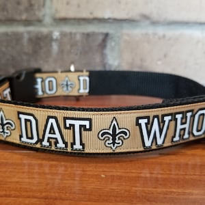 May include: A gold and black dog collar with the text "DAT WHO" and fleur-de-lis symbols.