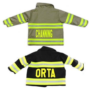 May include: Two miniature firefighter jackets, one khaki and one black. The khaki jacket has the name "CHANNING" in yellow block letters. Both jackets feature reflective yellow and silver stripes for safety.